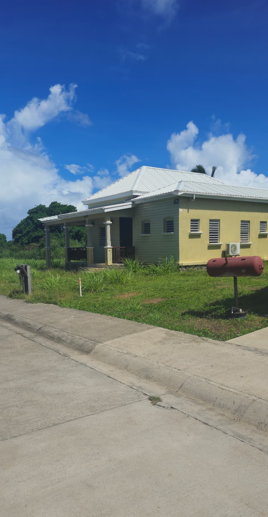 Pale cottage with a covered veranda and louvered windows on a grass lawn