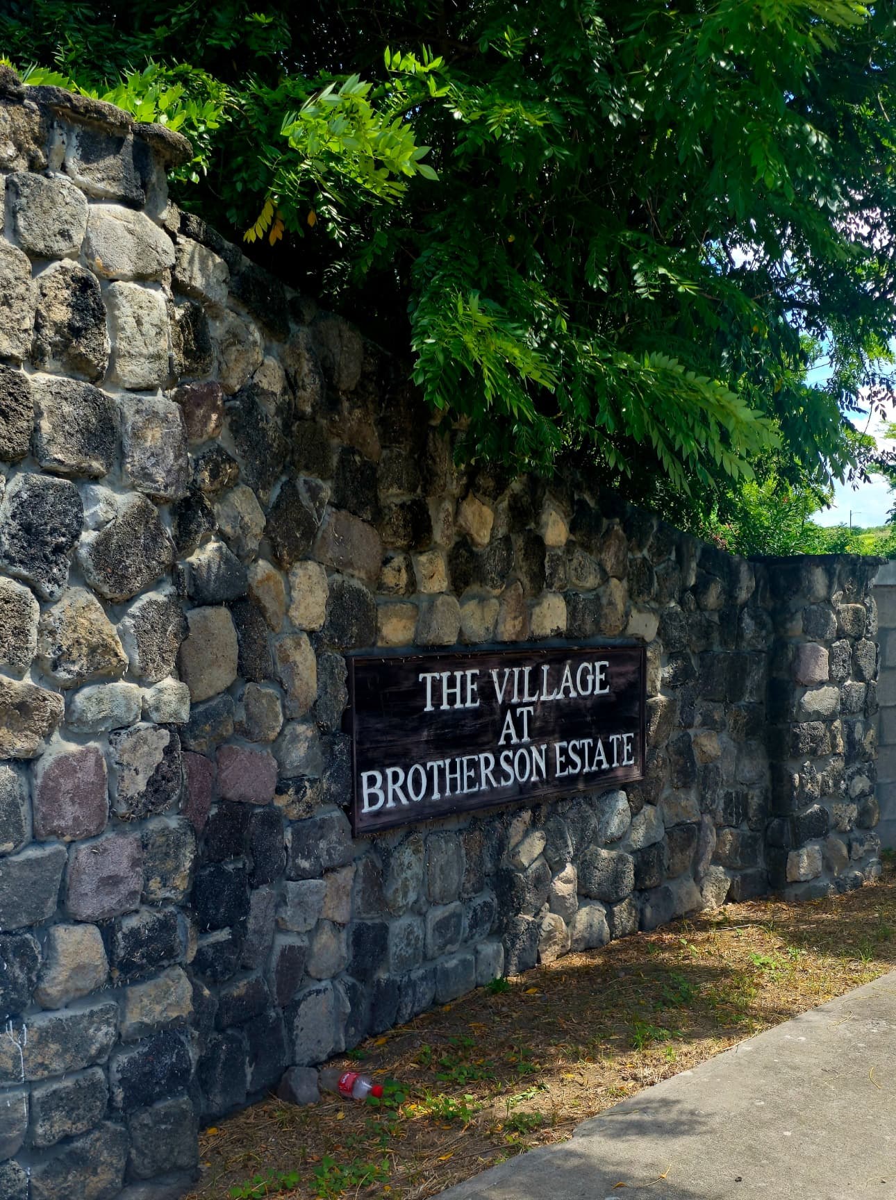 Stone entrance wall of The Village at Brotherson Estate with a dark estate sign